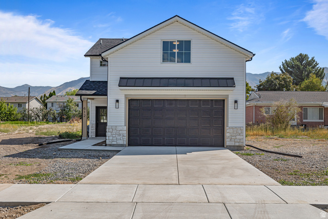 612 North 400 West Logan, UT 84321 - Photo 5 of 27 Modern farmhouse-style exterior with white siding, dark garage door, stone accents, and a covered entry