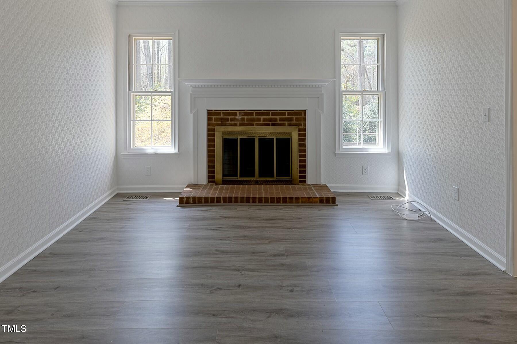 7605 Mine Valley Road Raleigh, NC 27615 - Photo 5 of 30 an empty room with wooden floor fireplace and windows