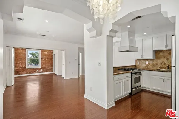 a kitchen with stainless steel appliances granite countertop a stove top oven a sink and a chandelier