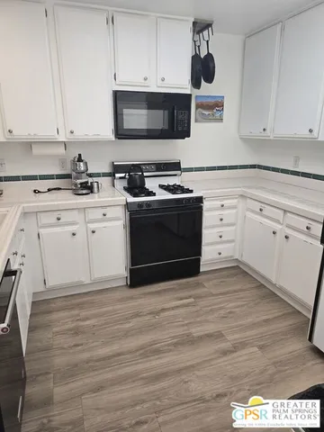 a kitchen with granite countertop a stove top oven a sink and white cabinets