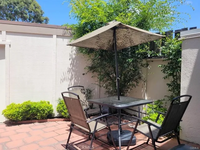 a backyard of a house with table and chairs under an umbrella