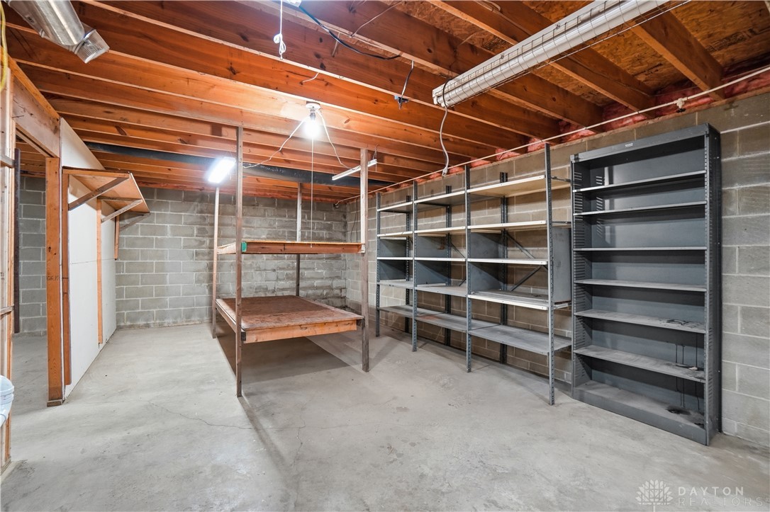 7553 Coffin Station Road Springfield, OH 45502 - Photo 80 of 95 This spacious basement offers ample storage potential with concrete flooring and exposed ceiling beams.
