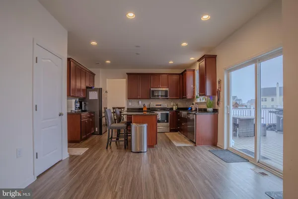 a kitchen with stainless steel appliances granite countertop a refrigerator oven a sink dishwasher a stove and a refrigerator with wooden floor