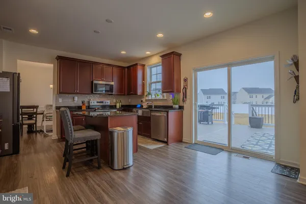 a kitchen with stainless steel appliances granite countertop wooden floors a refrigerator and a stove top oven