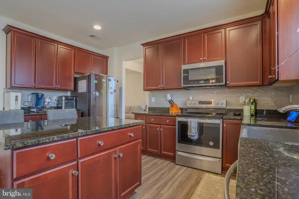 a kitchen with stainless steel appliances granite countertop a stove a sink dishwasher a refrigerator and a microwave