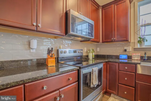 a kitchen with stainless steel appliances granite countertop a sink a stove and cabinets