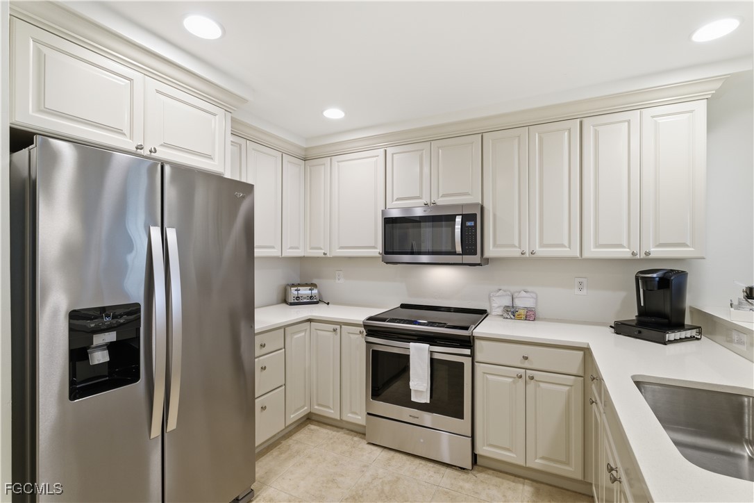 221 9th Street South, Unit 207 Naples, FL 34102 - Photo 17 of 38 a kitchen with white cabinets and stainless steel appliances