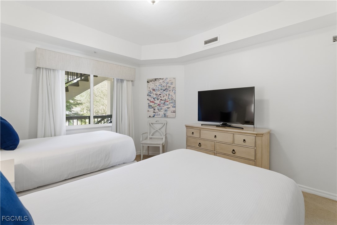 221 9th Street South, Unit 207 Naples, FL 34102 - Photo 23 of 38 a bedroom with two flat screen tv and a bed