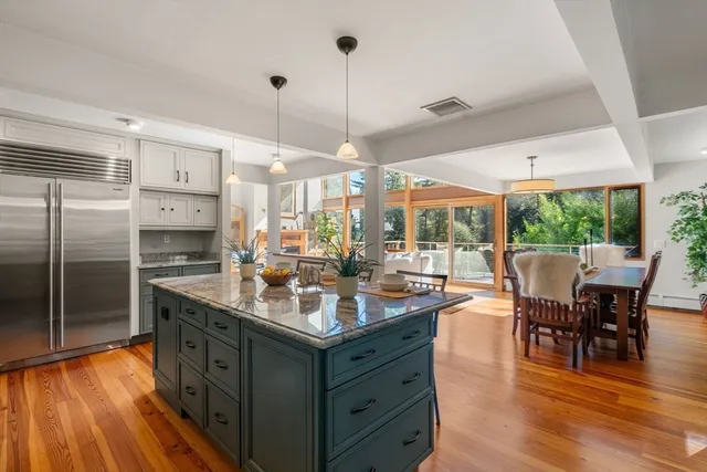 a kitchen with stainless steel appliances granite countertop a stove top oven a sink dishwasher a dining table and chairs with wooden floor