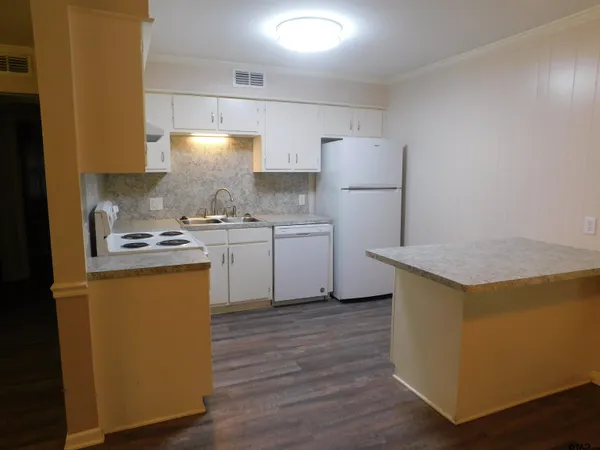 a kitchen with a sink a stove a refrigerator and white cabinets