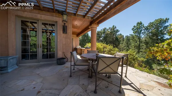 a patio with table and chairs and potted plants