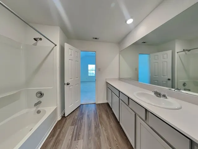 a bathroom with a double vanity sink a mirror and a bathtub