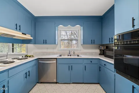 a kitchen with a stove a sink a window and a dining table