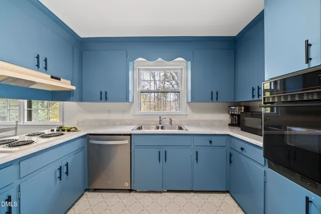 a kitchen with a stove a sink a window and a dining table