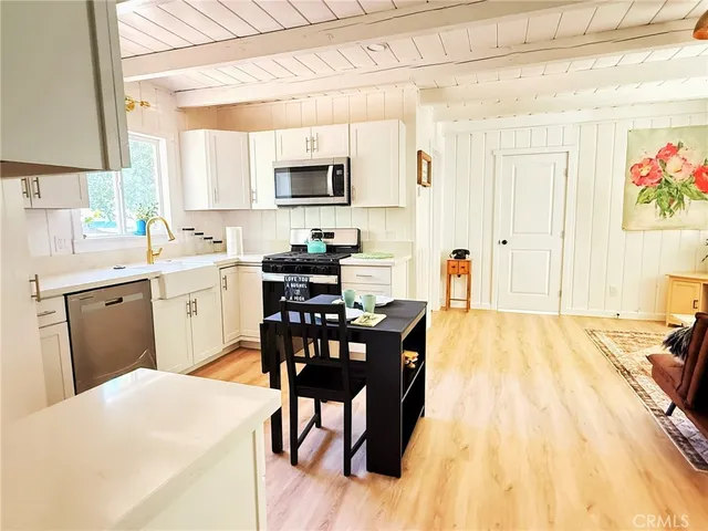 a kitchen with stainless steel appliances kitchen island granite countertop a sink a stove a dining table and chairs