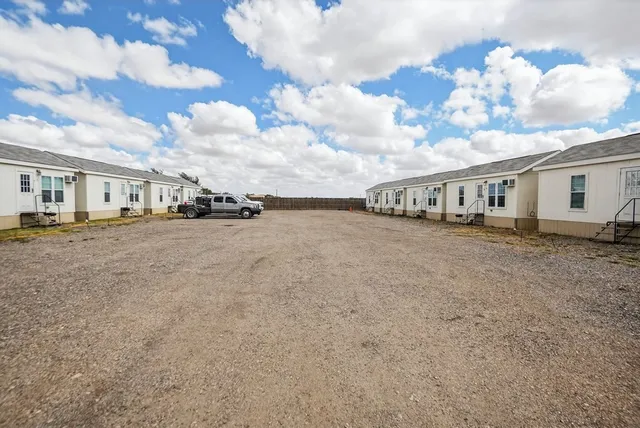 a view of white house with a big yard and large tree