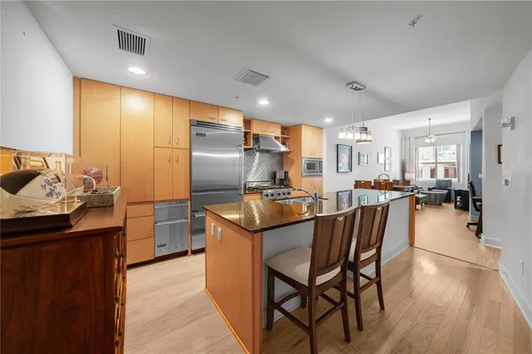 a kitchen with stainless steel appliances granite countertop a table chairs and a refrigerator
