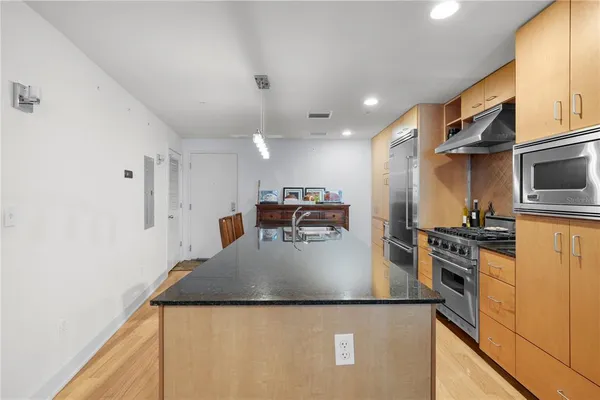 a kitchen with stainless steel appliances granite countertop a sink a stove and a refrigerator