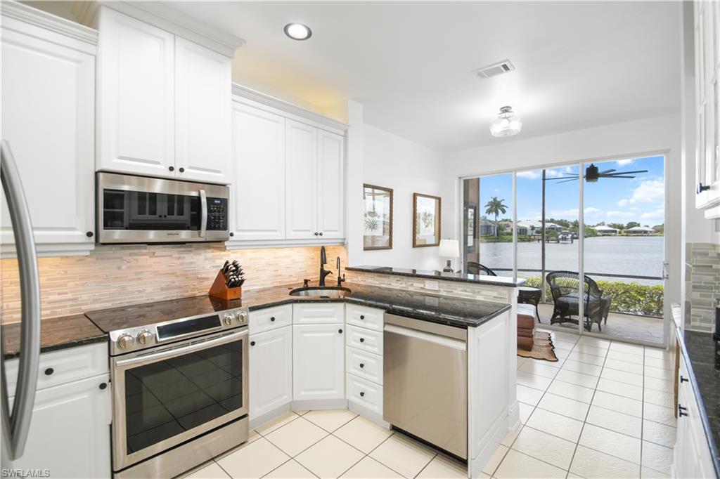 172 Eveningstar Cay Naples, FL 34114 - Photo 8 of 24 a kitchen with white cabinets and appliances