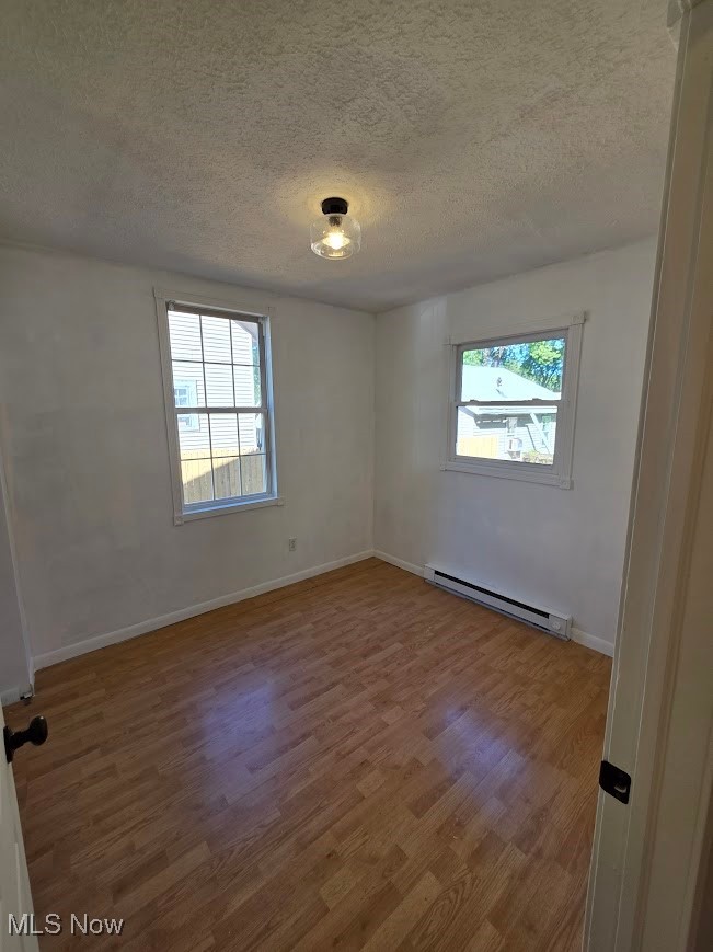 1445 Hubbard Road Madison, OH 44057 - Photo 15 of 21 Unfurnished room with light wood-style flooring, a baseboard radiator, and a textured ceiling