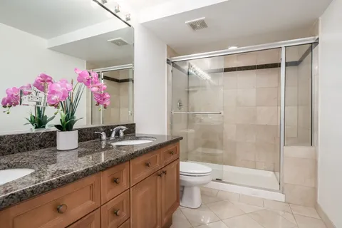 a bathroom with a granite countertop sink a toilet and shower