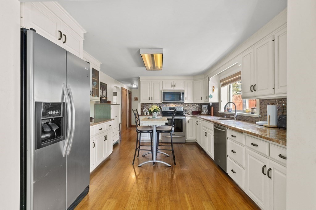 9 Lawrence Street Beverly, MA 01915 - Photo 9 of 42 a kitchen with stainless steel appliances a refrigerator a stove top oven a sink dishwasher and white cabinets with wooden floor