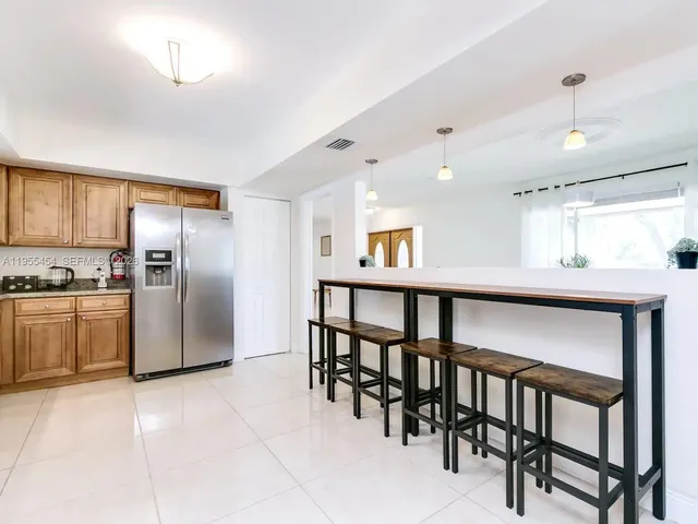 a kitchen with stainless steel appliances kitchen island granite countertop a table chairs sink and cabinets