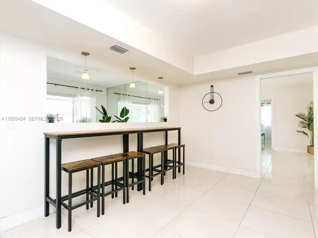 a kitchen with stainless steel appliances kitchen island granite countertop a table chairs and a refrigerator