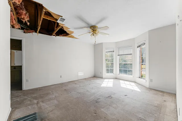 an empty room with windows and fan