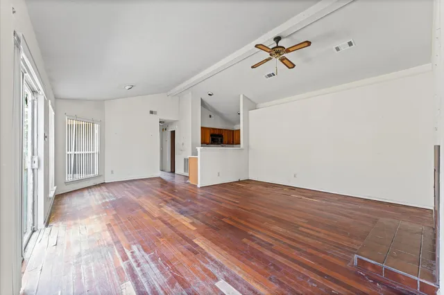 a view of a big room with wooden floors and windows