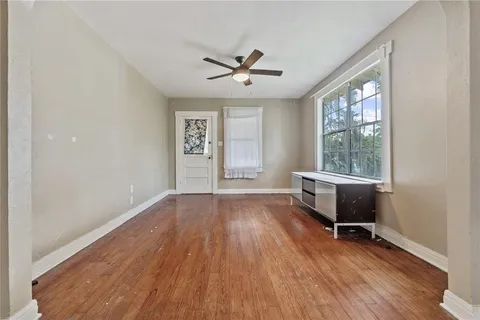 an empty room with wooden floor fan and windows
