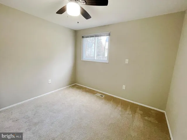 an empty room with a window and a fan