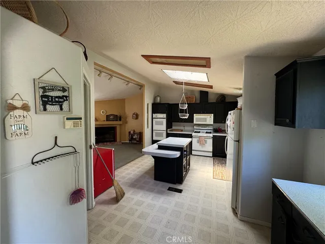 a kitchen view with stainless steel appliances kitchen island granite countertop a refrigerator and a stove
