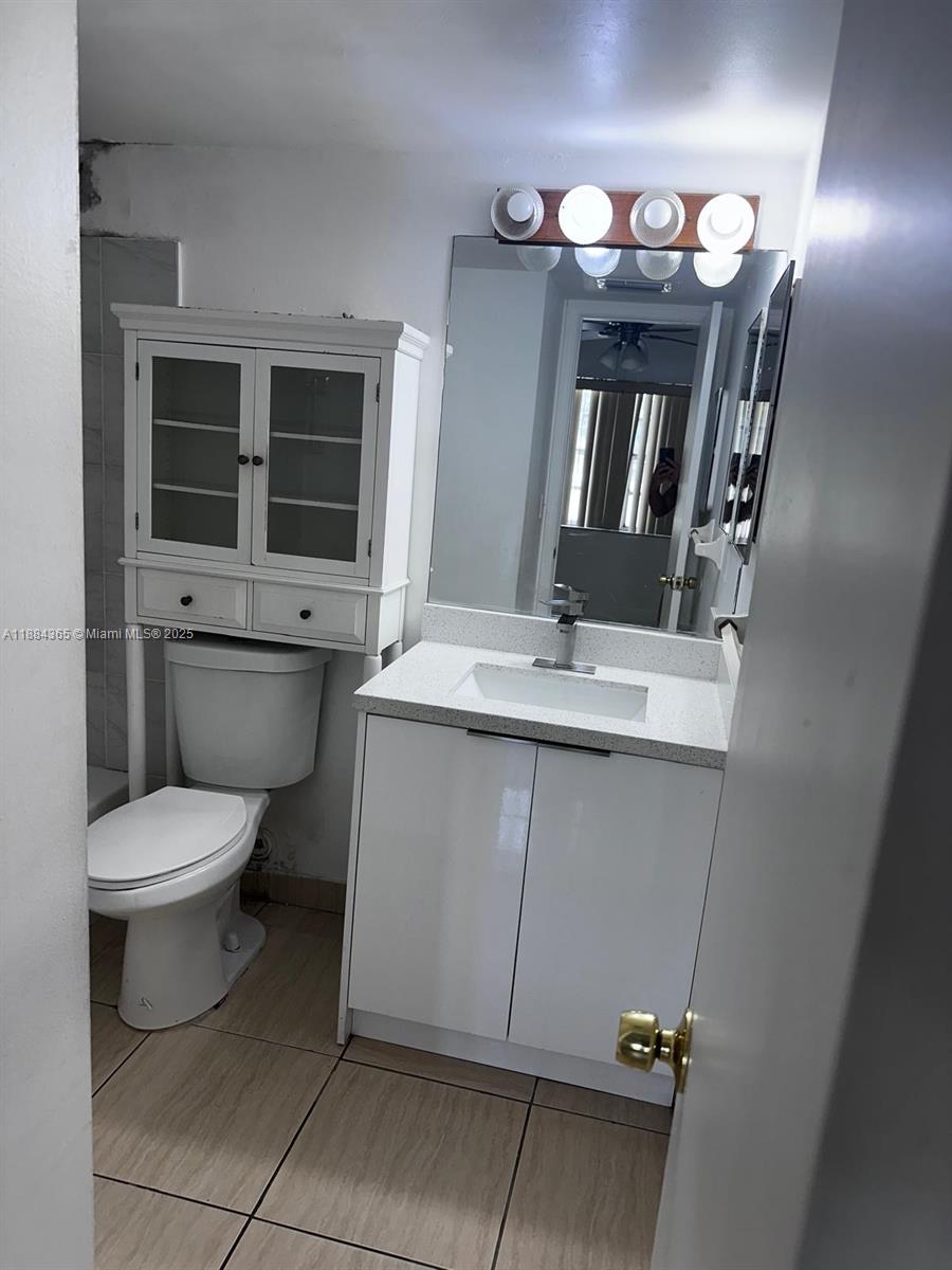 10124 Twin Lakes Drive, Unit 11D Coral Springs, FL 33071 - Photo 11 of 12 a bathroom with a toilet sink and mirror