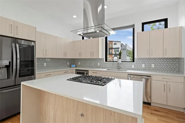 a kitchen with stainless steel appliances a refrigerator a sink dishwasher a stove and white cabinets with wooden floor