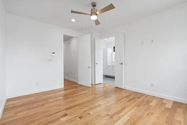 an empty room with wooden floor and ceiling fan