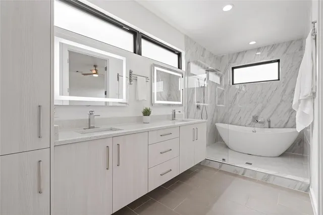 a spacious bathroom with a double vanity sink a large mirror and a bathtub