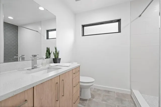 a bathroom with a granite countertop sink a toilet and mirror