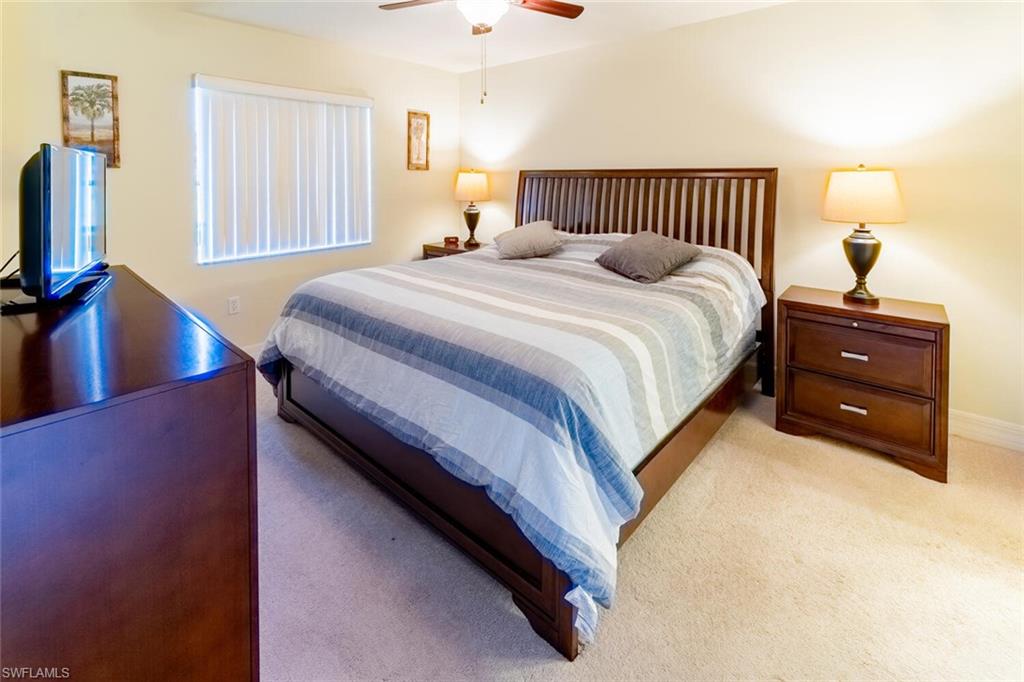 1100 Eastham Way, Unit A105 Naples, FL 34104 - Photo 13 of 27 a bedroom with a bed and a flat tv screen on dresser