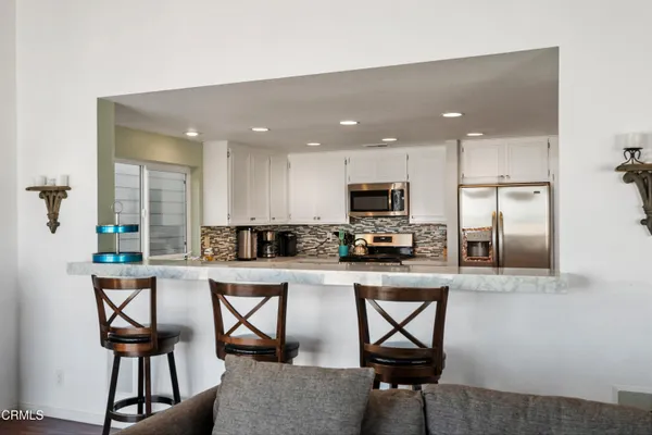 a kitchen with stainless steel appliances kitchen island granite countertop a refrigerator and microwave