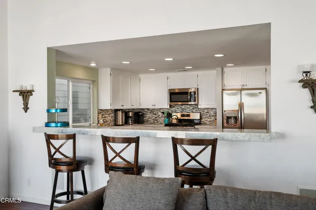 a kitchen with stainless steel appliances kitchen island granite countertop a refrigerator and microwave