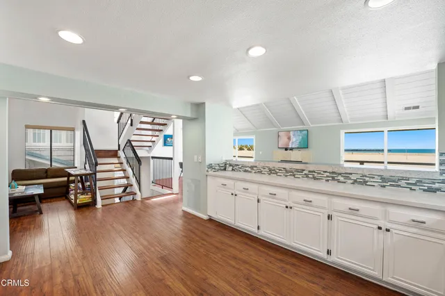 a living room with couches a coffee table and potted plants with wooden floor