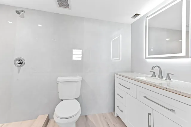 a white toilet sitting next to a bathroom sink and vanity