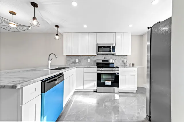a kitchen with stainless steel appliances granite countertop a stove a sink and a refrigerator