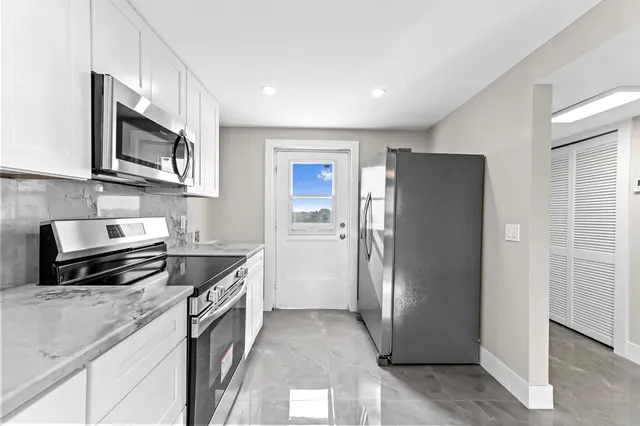a kitchen with stainless steel appliances granite countertop a refrigerator and a stove top oven