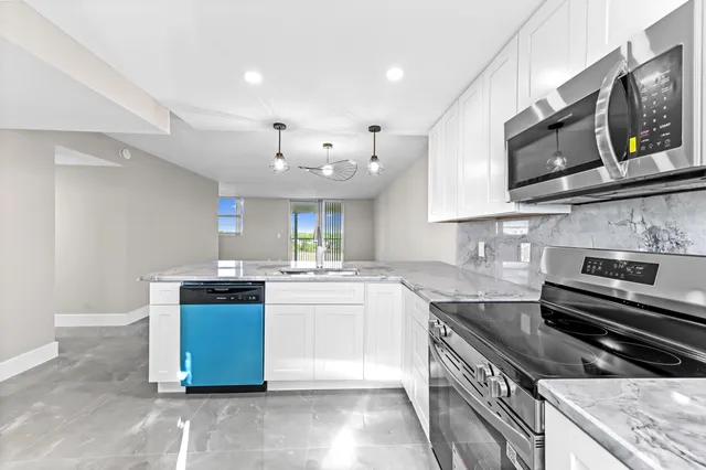 a kitchen with stainless steel appliances granite countertop a stove a sink and a microwave