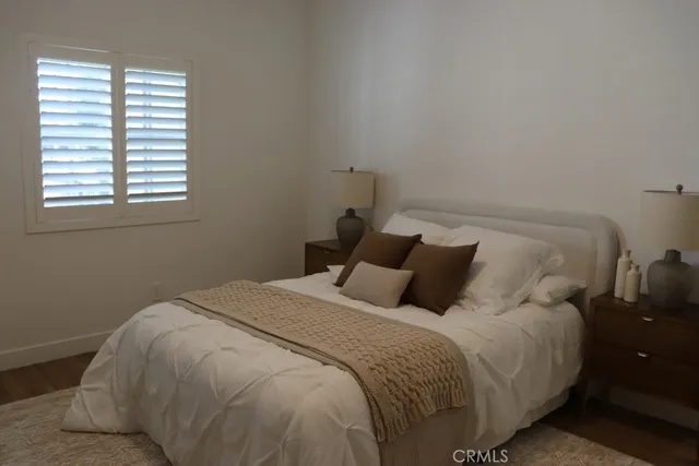 a bed sitting in a bedroom next to a window and potted plant on a table