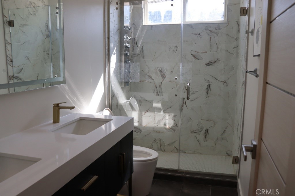 9103 Wystone Avenue Northridge, CA 91324 - Photo 35 of 59 a bathroom with a granite countertop sink toilet a mirror and shower