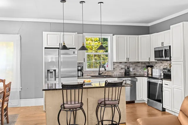 a kitchen with stainless steel appliances granite countertop a table chairs refrigerator and microwave