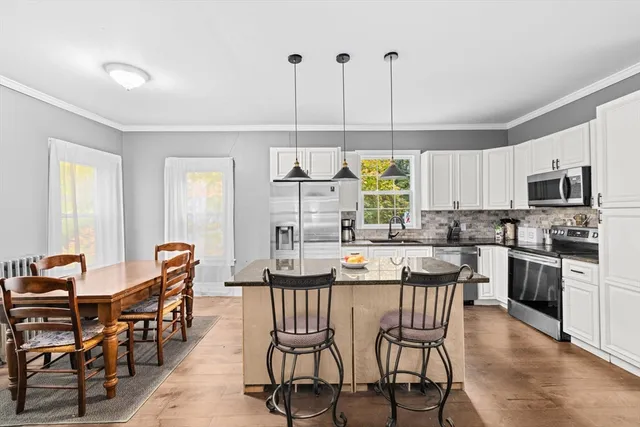a kitchen with stainless steel appliances a dining table chairs and granite counter tops